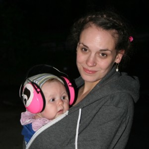 Frau mit Kind auf dem Arm, das Ohrenschützer trägt