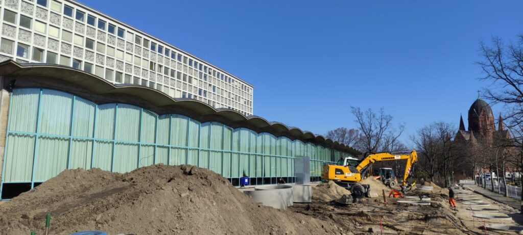 Baustelle mit Bagger, dahinter Lesesaal der AGB